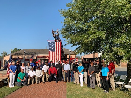 group of people standing in front of American flag in college courtyard