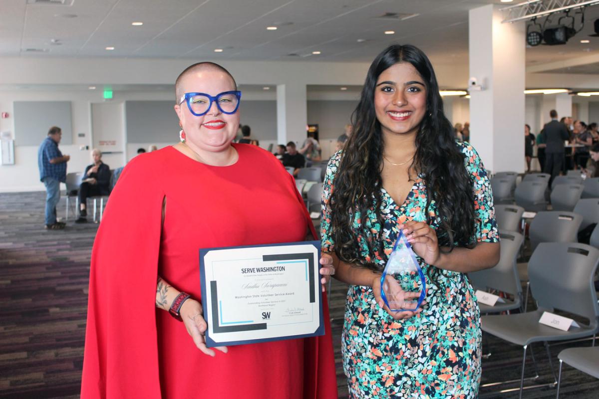 Serve Washington commissioner Ryan presenting a person with an award at a convention center