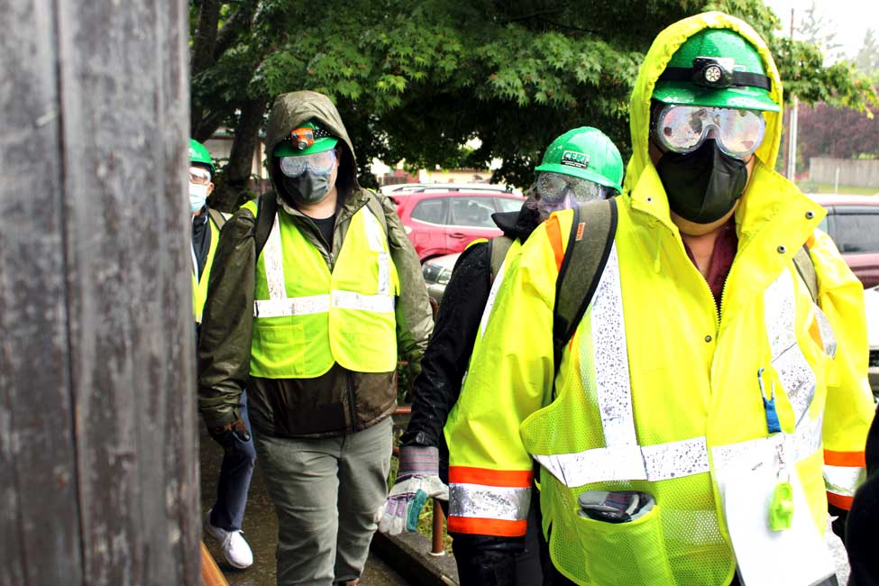 three CERT members walking in a line wearing goggles, hard hats and vests